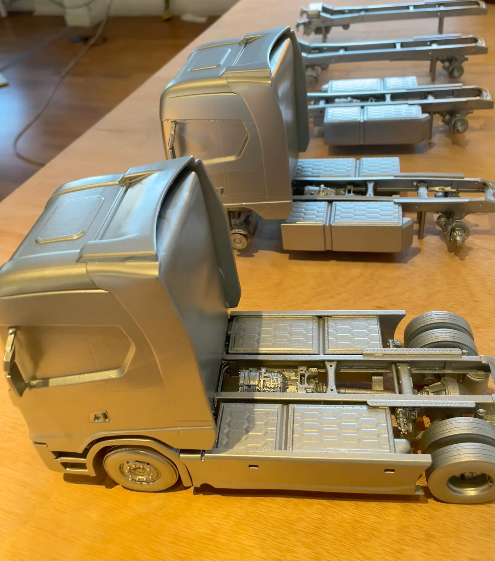 Två modeller av en ellastbil sedda snett från sidan, med chassi och batterilådor i fokus